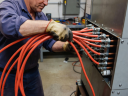 Certified electrician routing high-temperature silicone cables to a high-capacity heater terminal